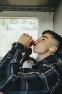 Side view of boy drinking juice from bottle in train