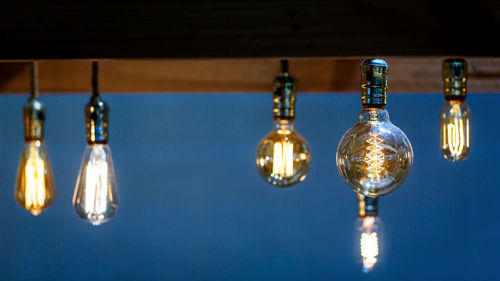 Close-up of illuminated light bulb hanging on ceiling