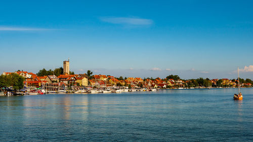 Sailboats in sea against buildings in city