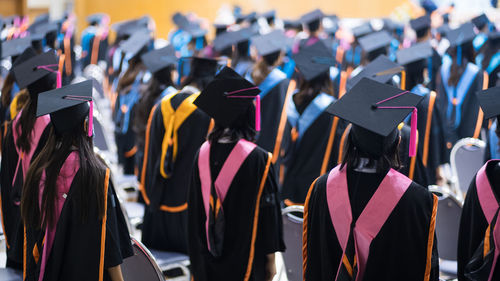 Women wearing graduation gown and mortarboard standing in university