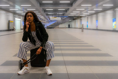 Side view of woman sitting at railroad station platform