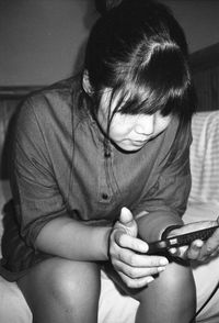 Rear view of girl looking down while sitting at home