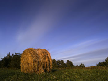 Hay bales on field against sky