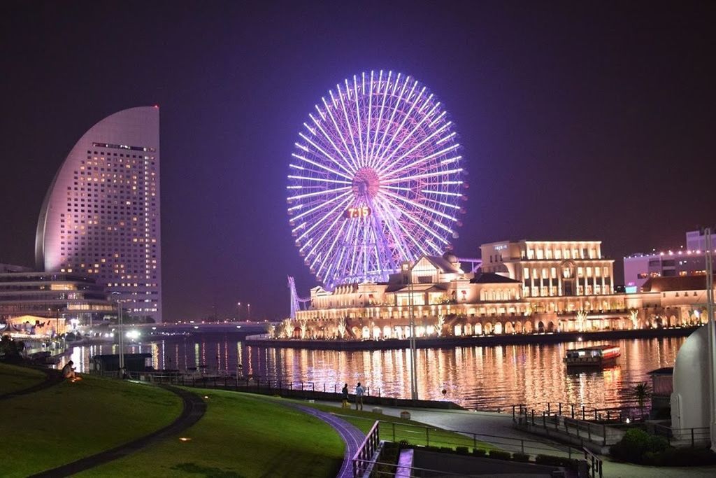 illuminated, night, ferris wheel, architecture, built structure, building exterior, amusement park, arts culture and entertainment, amusement park ride, city, sky, incidental people, multi colored, clear sky, outdoors, travel destinations, city life, circle, no people, low angle view