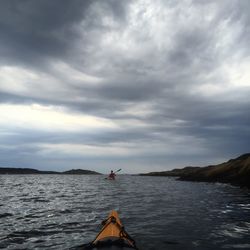 Boat sailing in sea against cloudy sky