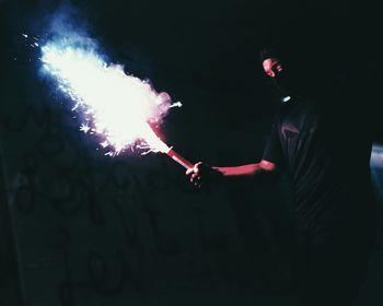 Man holding fire cracker at night