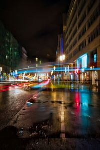 Light trails on city street by buildings at night