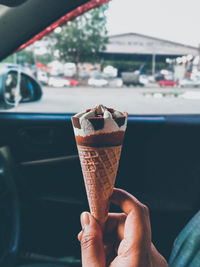 Close-up of hand holding ice cream cone in car