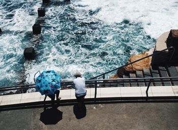 High angle view of friends standing at railing against sea