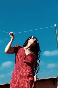 Young woman standing against clear blue sky