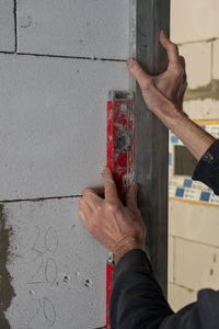 Man's hands pressed against the foam wall red building level. the concept of room renovation