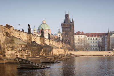 Low angle view of charles bridge and cathedral by river in city against clear sky