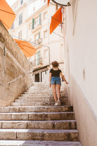 Back view of adventurous traveler woman walking upstairs in majorca