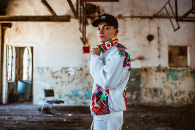 Side view of young man standing against built structure