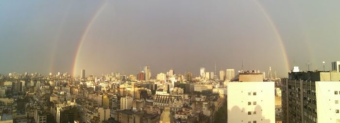 Aerial view of rainbow over buildings in city against sky