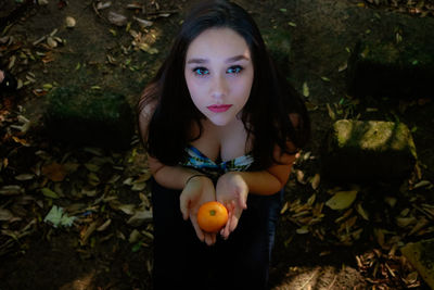 High angle portrait of beautiful woman kneeling with orange fruit