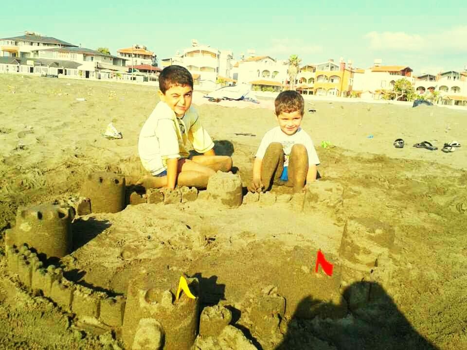 lifestyles, person, casual clothing, full length, leisure activity, young adult, young men, happiness, smiling, built structure, sand, portrait, building exterior, sitting, boys, mid adult