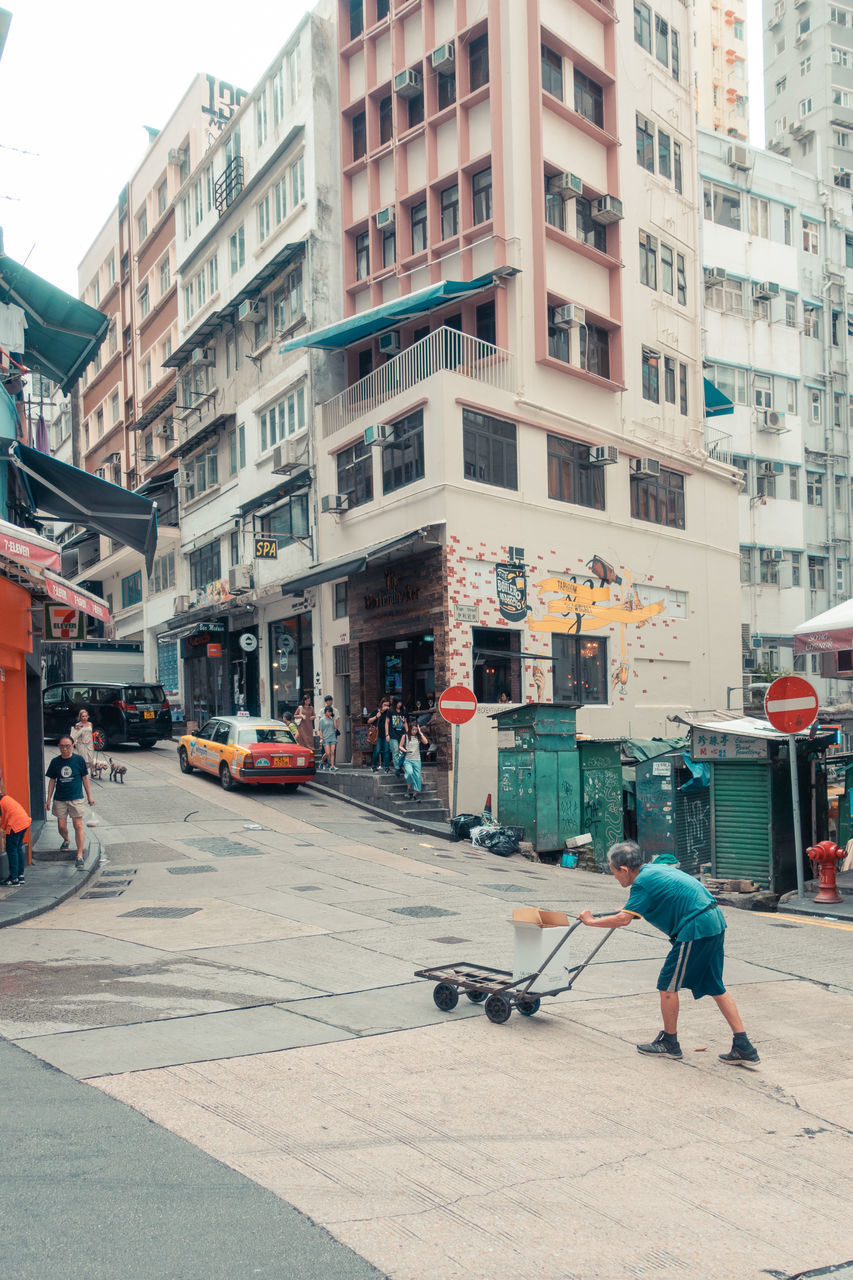 PEOPLE WALKING ON STREET AGAINST BUILDINGS IN CITY