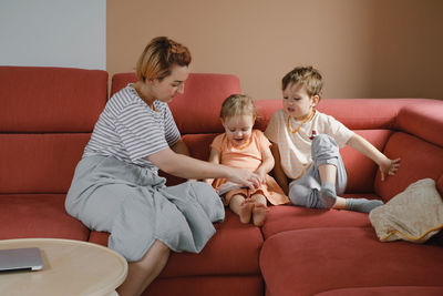 Mother reading book with two kids on sofa. happy family moments at home. spending time and educating