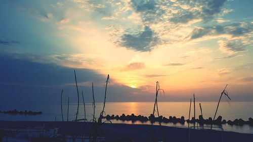 Silhouette sailboats in sea against sky during sunset