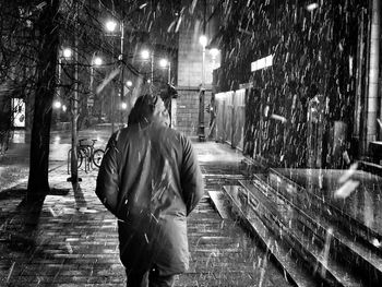 Rear view of man walking on street at night