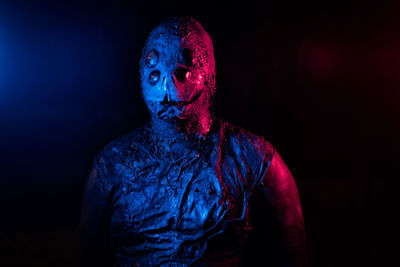 Portrait of man wearing mask against black background