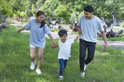 Full length of siblings running on grassy field