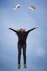 Low angle view of woman with arms raised against sky