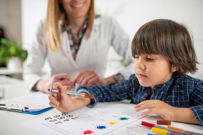 Close-up of boy drawing at desk in office