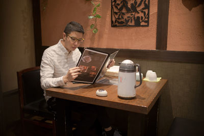 Man reading menu while sitting a table in restaurant