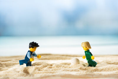 Boy toy on sand at beach against sky