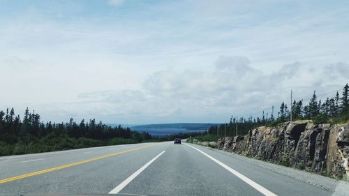 Road by trees against sky