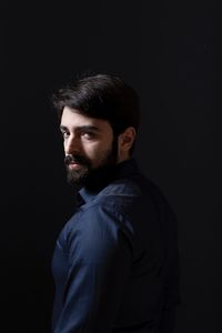 Portrait of man standing against black background