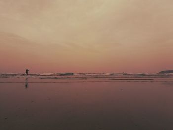 Silhouette person on beach against sky during sunset