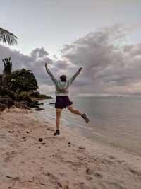 Full length of boy running at beach against sky during sunset