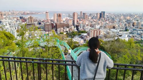 Rear view of woman standing by railing in city