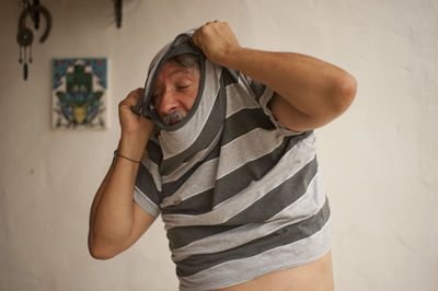 Midsection of man standing against wall at home