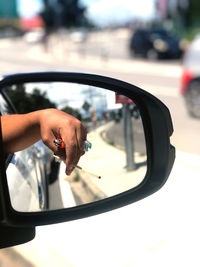 Close-up of hand holding side-view mirror