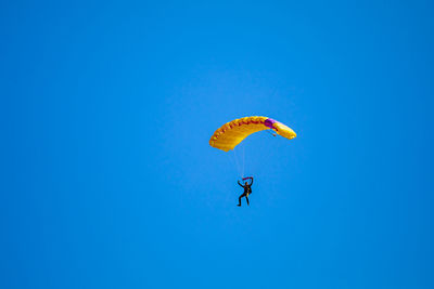 Low angle view of person paragliding against clear blue sky