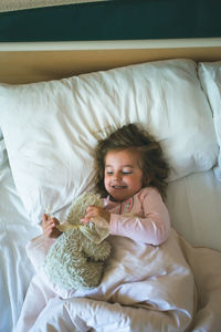 Girl lying on bed with stuffed toy at home