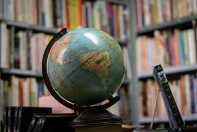 Close-up of globe against bookshelf at library