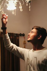 Young man touching chandelier at home