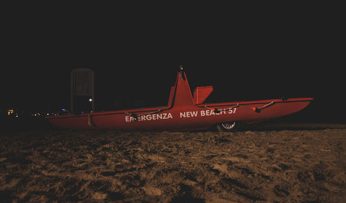 Illuminated text on beach against sky at night