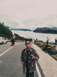 Young man standing on road against sky