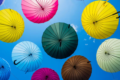 Low angle view of multi colored umbrellas against blue sky