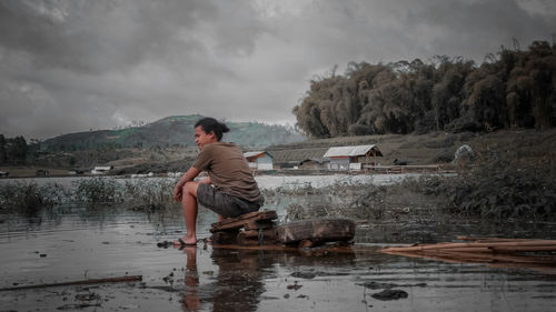 Side view of man in lake against sky