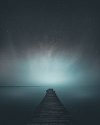 Pier over sea against sky at night