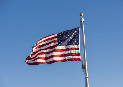 Low angle view of american flag against clear blue sky