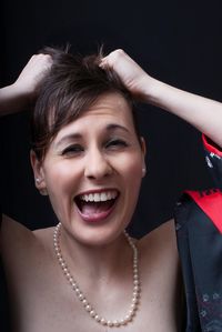 Close-up of frustrated woman pulling her hair against black background