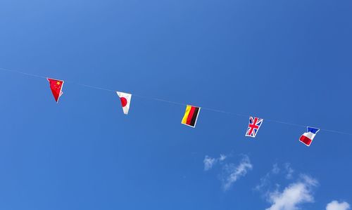 Low angle view of flags hanging against clear blue sky